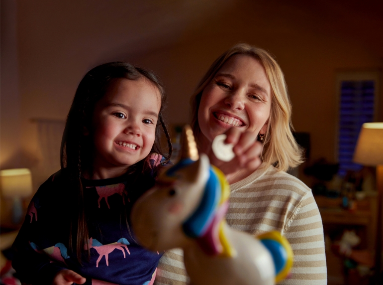 Young child in a unicorn costume at a table with a drink in a mug